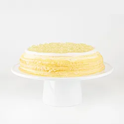 A Lady M Champagne Mille Crêpes on top a white cake stand.