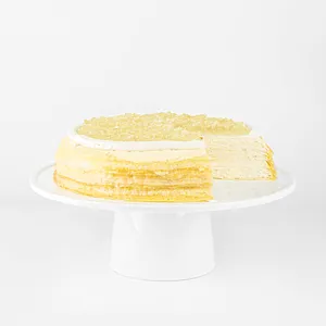 A sliced into Lady M Champagne Mille Crêpes on top a white cake stand.