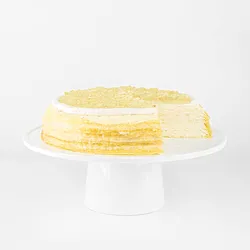 A sliced into Lady M Champagne Mille Crêpes on top a white cake stand.