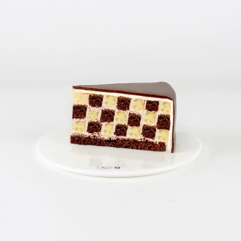 A Lady M Checkers slice on top a white round plate.