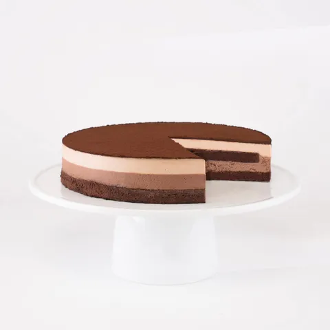A sliced into Lady M Chocolate Arc-en-Ciel on top a white cake stand.