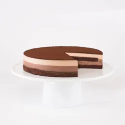 A sliced into Lady M Chocolate Arc-en-Ciel on top a white cake stand.