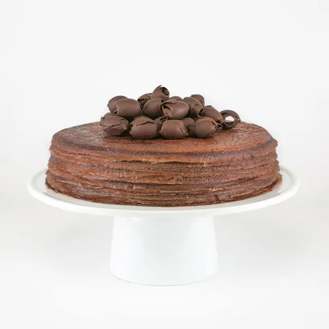 A Lady M Chocolate Mille Crêpes on top a white cake stand.