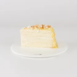 A slice of Lady M's Coconut Mille Crêpes on a white plate.