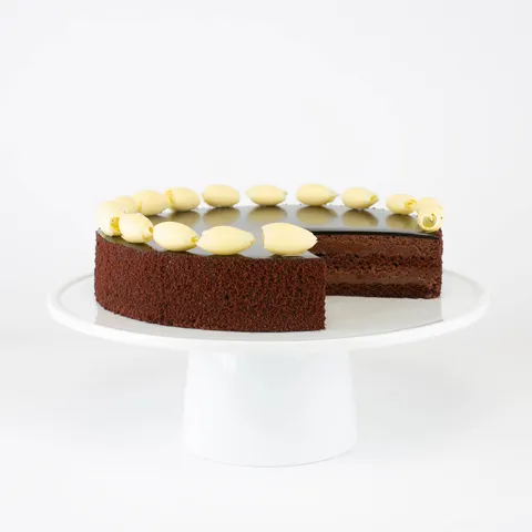 A sliced into Lady M Couronne du Chocolat on top a white cake stand.
