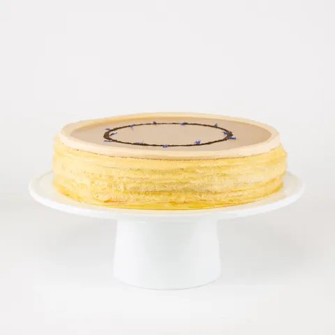 A Lady M Earl Grey Mille Crêpes on top a white cake stand.