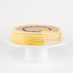 A sliced into Lady M Earl Grey Mille Crêpes on top a white cake stand.