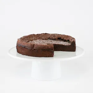 A sliced into Lady M Flourless Chocolate Cake on top a white cake stand.