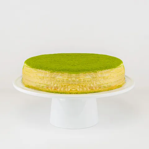 A Lady M Green Tea Mille Crêpes on top a white cake stand.