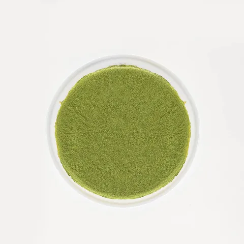 A top-down shot of a Lady M Green Tea Mille Crêpes on top a white cake stand.