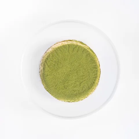 A top-down shot of a 6-inch Lady M Green Tea Mille Crêpes on top a white cake stand.