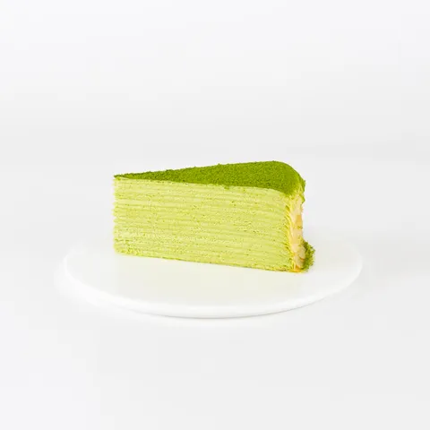 A Lady M Green Tea Mille Crêpes slice on top a white round plate.