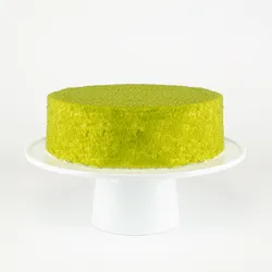 A Lady M Green Tea Mousse Cake on top a white cake stand.