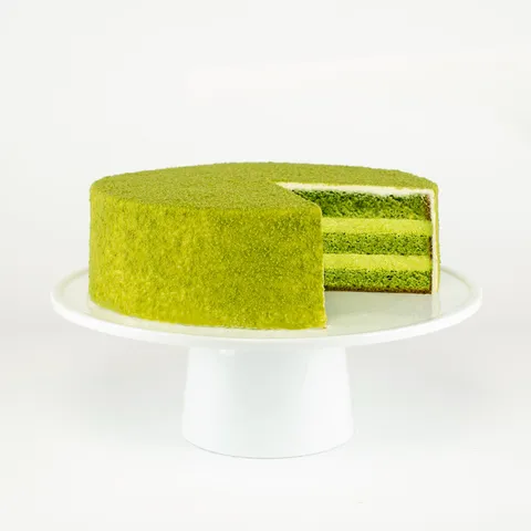 A sliced into Lady M Green Tea Mousse Cake on top a white cake stand.