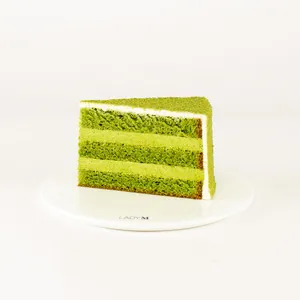 A Lady M Green Tea Mousse Cake slice on top a white round plate.