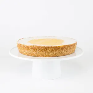 A Lady M Passion Fruit Cheesecake on top a white cake stand.