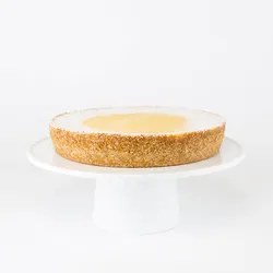 A Lady M Passion Fruit Cheesecake on top a white cake stand.