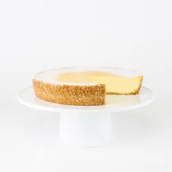 A sliced into Lady M Passion Fruit Cheesecake on top a white cake stand.