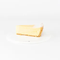 A Lady M Passion Fruit Cheesecake slice on top a white round plate.