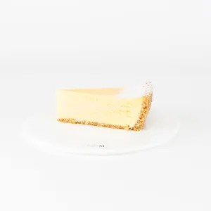A Lady M Passion Fruit Cheesecake slice on top a white round plate.
