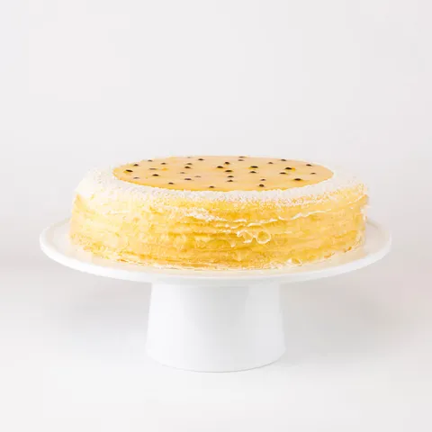 A Lady M Passion Fruit Mille Crêpes on top a white cake stand.