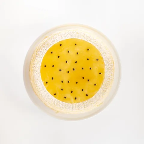 A top-down shot of a Lady M Passion Fruit Mille Crêpes on top a white cake stand.