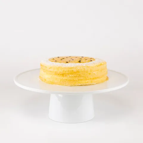 A 6-inch Lady M Passion Fruit Mille Crêpes on top a white cake stand.