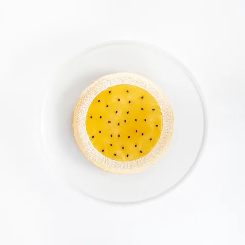 A top-down shot of a 6-inch Lady M Passion Fruit Mille Crêpes on top a white cake stand.