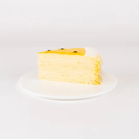 A Lady M Passion Fruit Mille Crêpes slice on top a white round plate.
