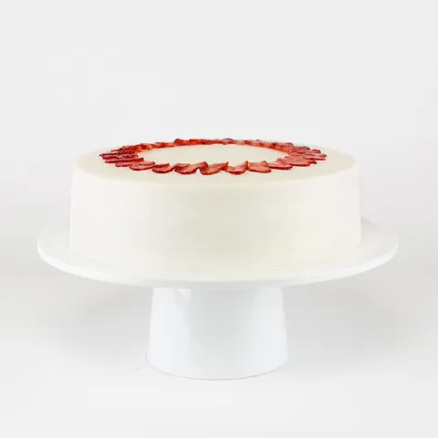 A Lady M Strawberry Shortcake on top a white cake stand.
