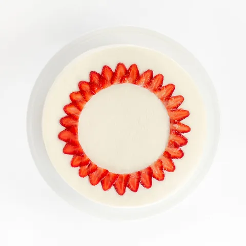 A top-down shot of a Lady M Strawberry Shortcake on top a white cake stand.
