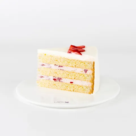 A Lady M Strawberry Shortcake slice on top a white round plate.