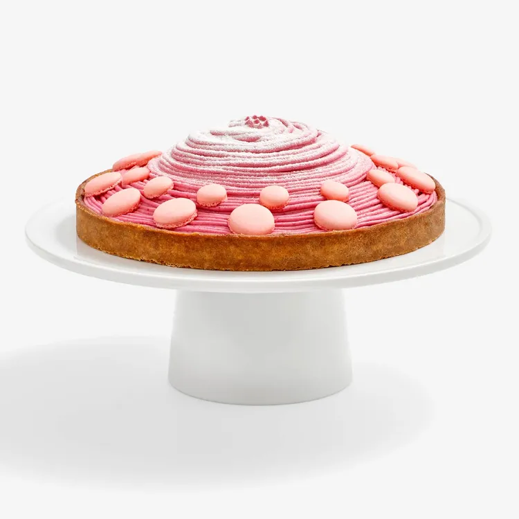 Berry Mont Blanc Tart featuring a tart crust, a four-berry mousse piped high, baby pink macaron shells and powdered sugar.