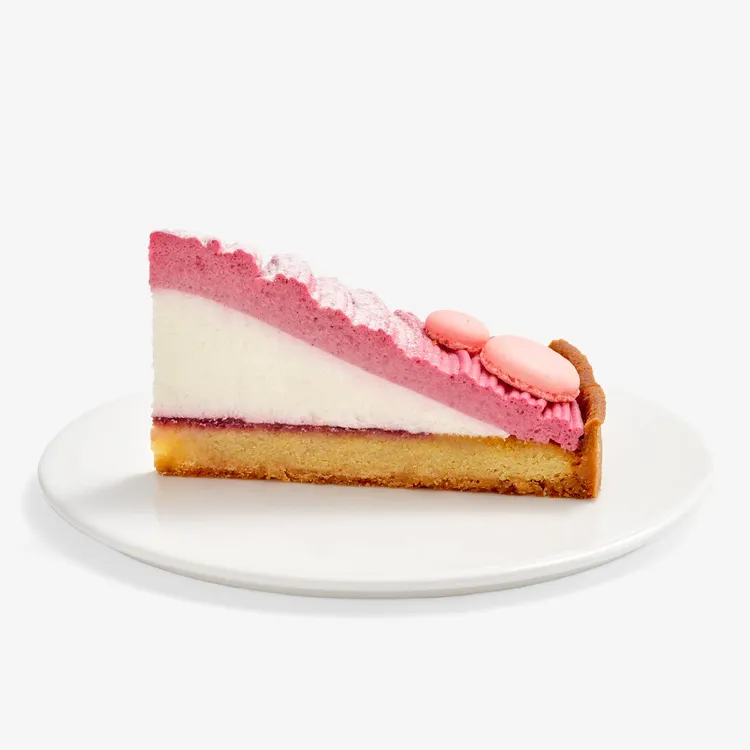 Berry Mont Blanc Tart slice featuring a tart curst, fresh cream center, a four-berry mousse, baby pink macaron shells and powdered sugar.