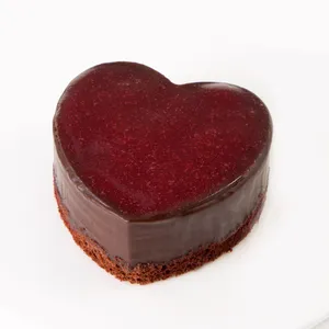 A Lady M Framboise au Chocolat Valentine Heart on top a white cake plate.