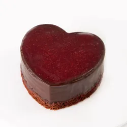 A Lady M Framboise au Chocolat Valentine Heart on top a white cake plate.