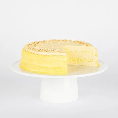 A thumbnail shot of a sliced into Lady M Tres Leches Mille Crêpes on top a white cake stand.