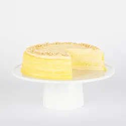 A thumbnail shot of a sliced into Lady M Tres Leches Mille Crêpes on top a white cake stand.