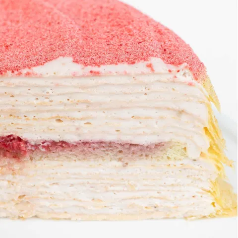 Detail shot of Strawberry Swirl Mille Crêpes. Layers of crêpes, sponge cake, cream, & strawberries.