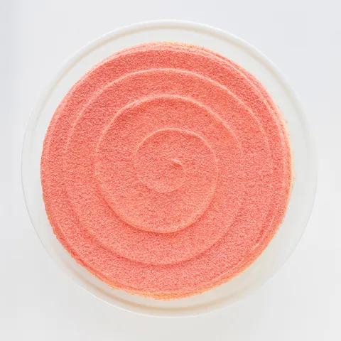 A top-down shot of a Lady M Strawberry Swirl Mille Crêpes on top a white cake stand.