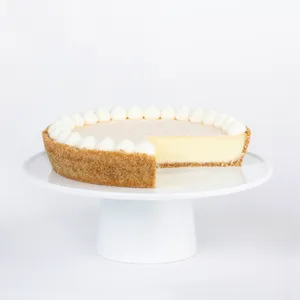 A thumbnail shot of a sliced into Lady M Coconut Cheesecake on top a white cake stand.