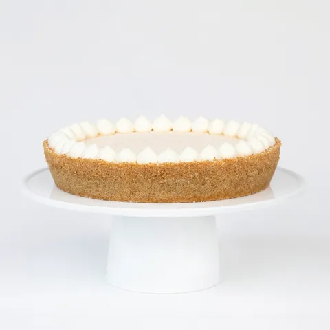 A thumbnail shot of a Lady M Coconut Cheesecake on top a white cake stand.