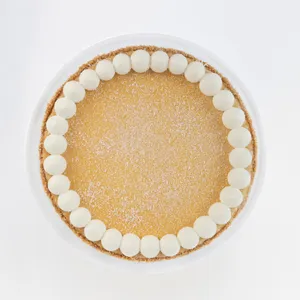 A top-down shot of a Lady M Coconut Cheesecake on top a white cake stand.