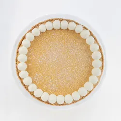 A top-down shot of a Lady M Coconut Cheesecake on top a white cake stand.