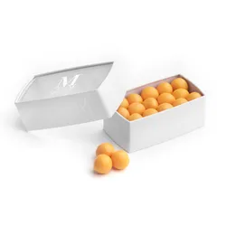 A Lady M Mango Jelly Pearl Bon Bons encased inside a half-opened packaging with a Lady M logo.