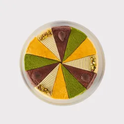 A top-down shot of a Lady M Slice of the Best: Celebration Collection on top a white cake stand.