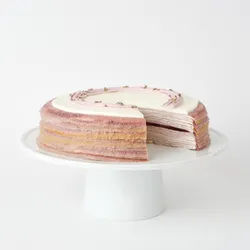 A thumbnail shot of a sliced into Lady M Lavender Mille Crêpes on top a white cake stand.