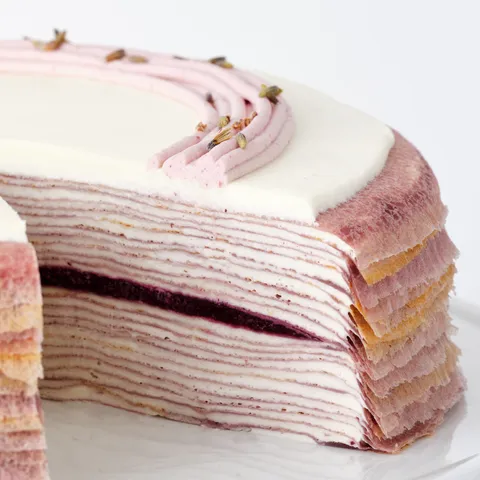Detail shot of a Lady M Lavender Mille Crêpes. Layers of crêpes, cream, and blackberry jelly.