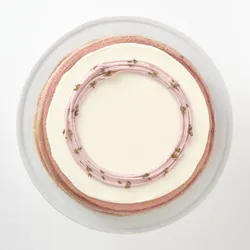 A top-down shot of a Lady M Lavender Mille Crêpes on top a white cake stand.