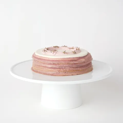 A thumbnail shot of a 6-inch Lady M Lavender Mille Crêpes on top a white cake stand.